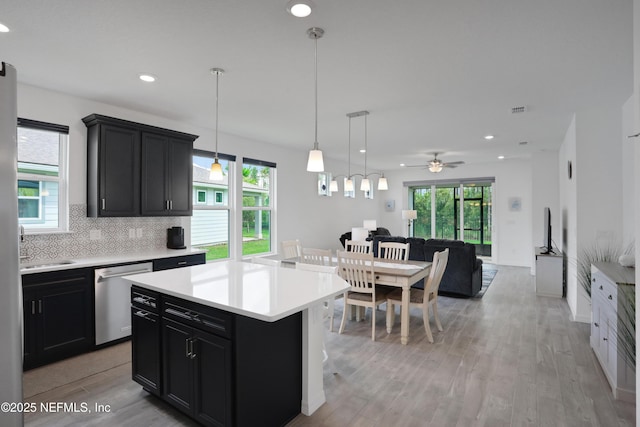 564 Jubilee Cir, Yulee, FL 32097 - kitchen with stainless steel dishwasher, dark cabinetry, light countertops, open floor plan, and light wood-type flooring