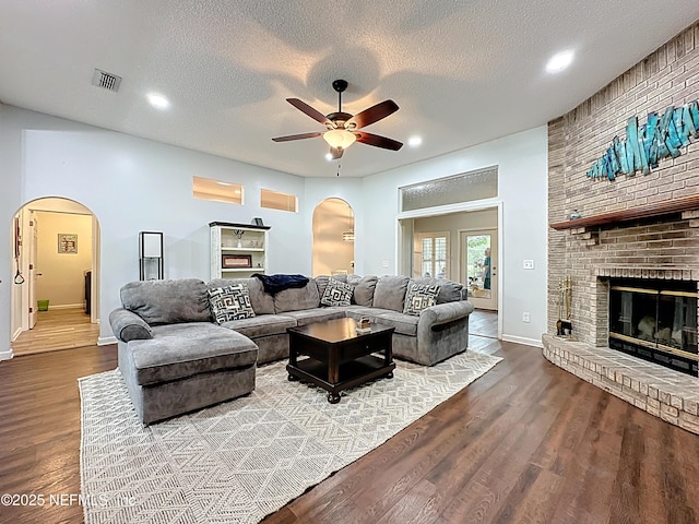 3923 Eden Estate Trl, Middleburg, FL 32068 - living room with arched walkways, a ceiling fan, a brick fireplace, wood finished floors, and baseboards