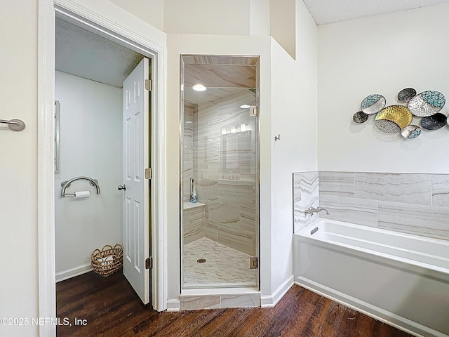 3923 Eden Estate Trl, Middleburg, FL 32068 - bathroom featuring wood finished floors, a stall shower, a bath, and baseboards