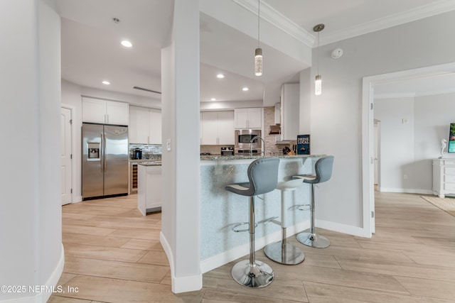 1925 S Atlantic Ave Unit 810, Daytona Beach Shores, FL 32118 - kitchen featuring stainless steel appliances, light wood-style flooring, crown molding, white cabinets, and light stone counters