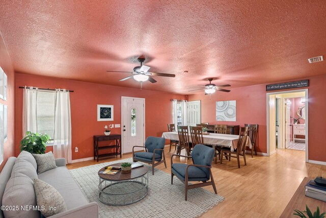 2443 SE 150th St, Starke, FL 32091 - living room featuring a textured ceiling, healthy amount of natural light, a ceiling fan, and light wood-style flooring