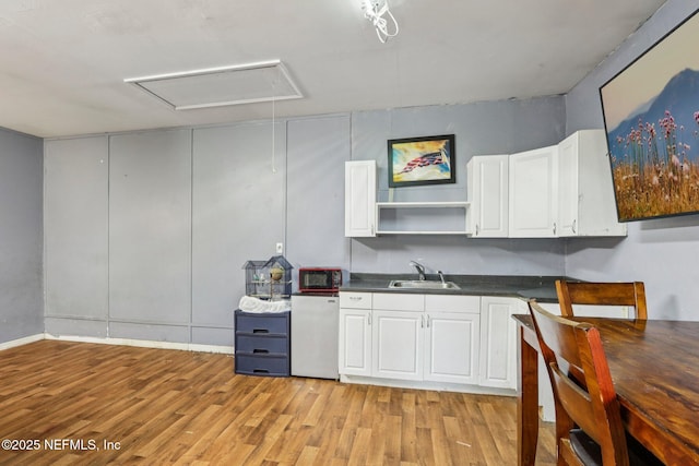 2443 SE 150th St, Starke, FL 32091 - kitchen featuring light wood-type flooring, dark countertops, and white cabinets