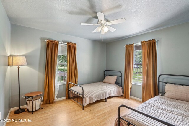 2443 SE 150th St, Starke, FL 32091 - bedroom with multiple windows, light wood-style flooring, a textured ceiling, and a ceiling fan