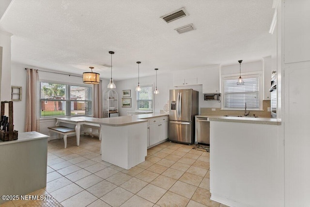 416 Margaret St, Neptune Beach, FL 32266 - kitchen featuring stainless steel appliances, a peninsula, light countertops, white cabinets, and a textured ceiling