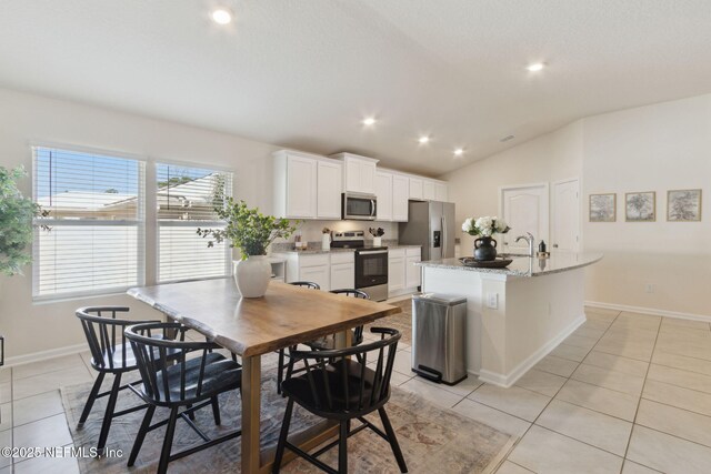 14 Rambling Ln, Palm Coast, FL 32164 - kitchen featuring stainless steel appliances, light tile patterned floors, a center island with sink, white cabinets, and lofted ceiling