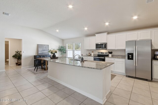 14 Rambling Ln, Palm Coast, FL 32164 - kitchen featuring stainless steel appliances, a sink, light tile patterned floors, white cabinets, and vaulted ceiling