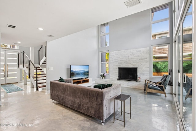 248 11th St, Atlantic Beach, FL 32233 - living area featuring healthy amount of natural light, concrete floors, stairway, a fireplace, and a towering ceiling