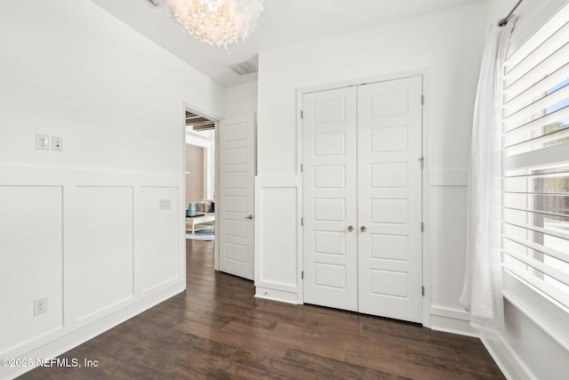97 Marquesa Cir, Saint Johns, FL 32259 - unfurnished bedroom featuring a chandelier, dark wood-style floors, a closet, a decorative wall, and a wainscoted wall