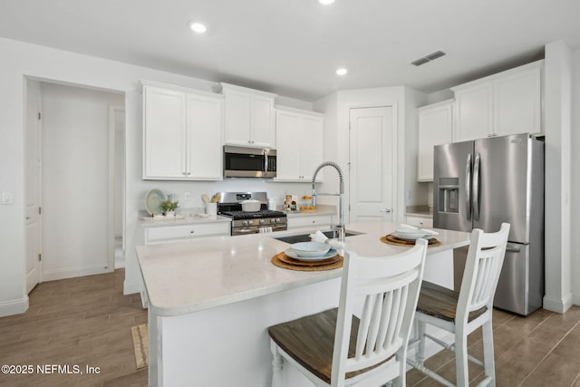 220 Killarney Ave, Saint Johns, FL 32259 - kitchen with appliances with stainless steel finishes, light wood-style floors, white cabinets, a center island with sink, and recessed lighting