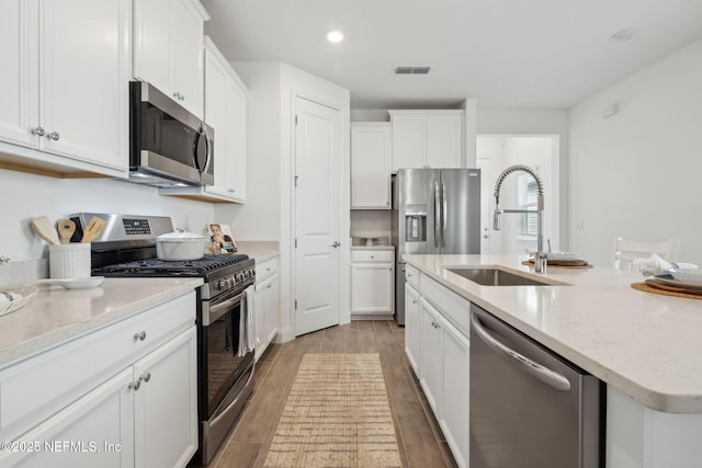 220 Killarney Ave, Saint Johns, FL 32259 - kitchen featuring appliances with stainless steel finishes, white cabinets, light wood-type flooring, a kitchen island with sink, and recessed lighting