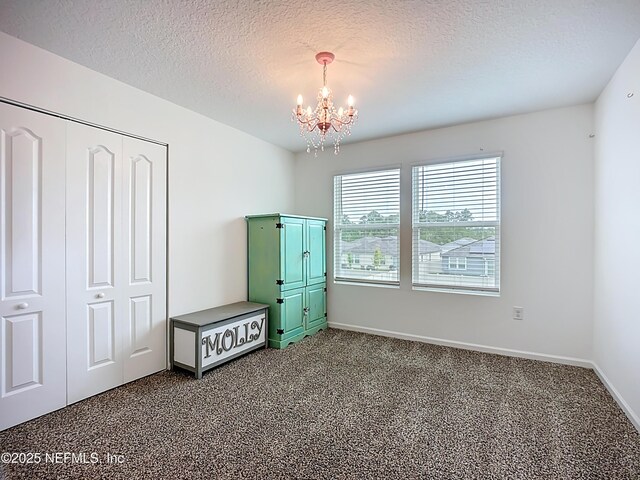 65274 Forest Glen Ln, Yulee, FL 32097 - unfurnished bedroom featuring a chandelier, dark colored carpet, a textured ceiling, baseboards, and a closet