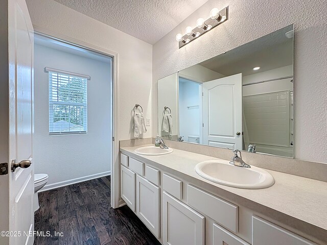 65274 Forest Glen Ln, Yulee, FL 32097 - bathroom with double vanity, toilet, a textured wall, wood finished floors, and a textured ceiling