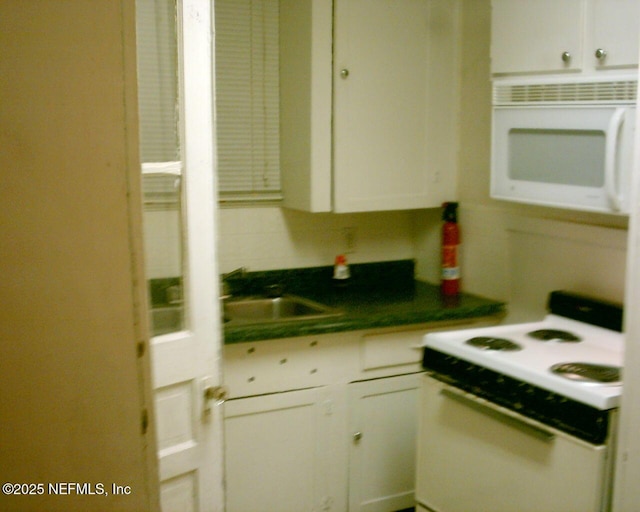 1050 Alderside St, Jacksonville, FL 32208 - kitchen with white appliances, white cabinets, a sink, and dark countertops