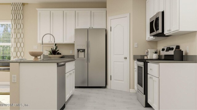 100 Round Robin Run, Saint Johns, FL 32259 - kitchen featuring appliances with stainless steel finishes, dark countertops, white cabinets, light wood finished floors, and a peninsula