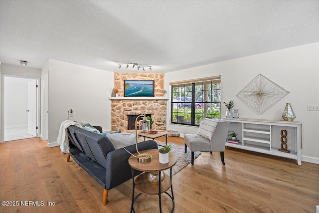 100 Palmera Ct, Ponte Vedra Beach, FL 32082 - living room featuring wood finished floors, a textured ceiling, a stone fireplace, baseboards, and track lighting