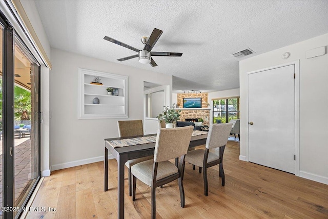 100 Palmera Ct, Ponte Vedra Beach, FL 32082 - dining area featuring a textured ceiling, light wood-style floors, ceiling fan, baseboards, and a fireplace