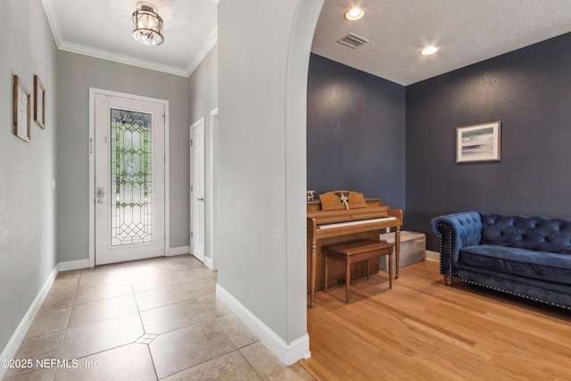96266 Dowling Dr, Yulee, FL 32097 - foyer featuring arched walkways, baseboards, crown molding, a textured ceiling, and light tile patterned floors