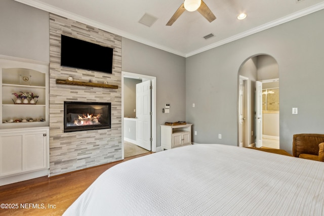 96266 Dowling Dr, Yulee, FL 32097 - bedroom featuring wood finished floors, a tiled fireplace, arched walkways, crown molding, and ensuite bath