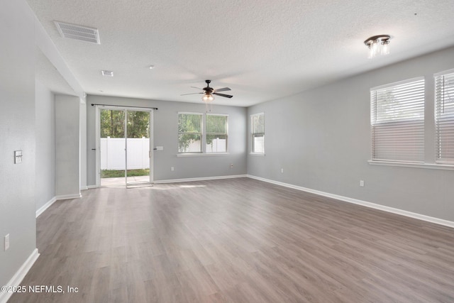 4916 Creek Bluff Ln, Middleburg, FL 32068 - empty room featuring a ceiling fan, plenty of natural light, wood finished floors, a textured ceiling, and baseboards