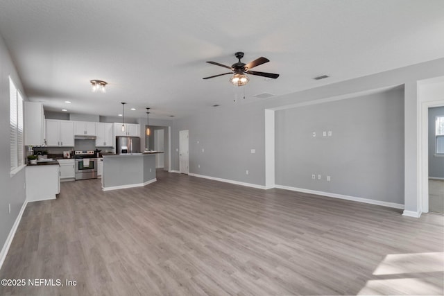 4916 Creek Bluff Ln, Middleburg, FL 32068 - unfurnished living room featuring ceiling fan, baseboards, light wood-type flooring, and plenty of natural light