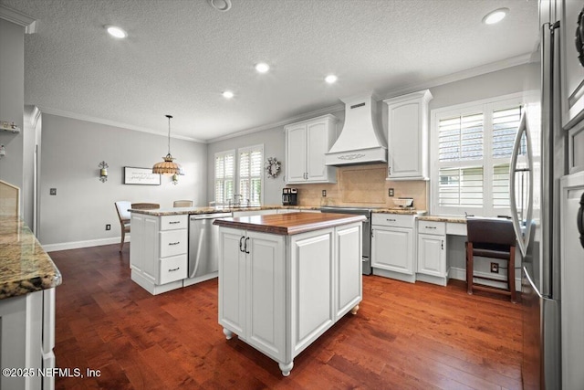 1714 Chatham Village Dr, Fleming Island, FL 32003 - kitchen featuring custom exhaust hood, stainless steel appliances, ornamental molding, a center island, and dark wood-style flooring
