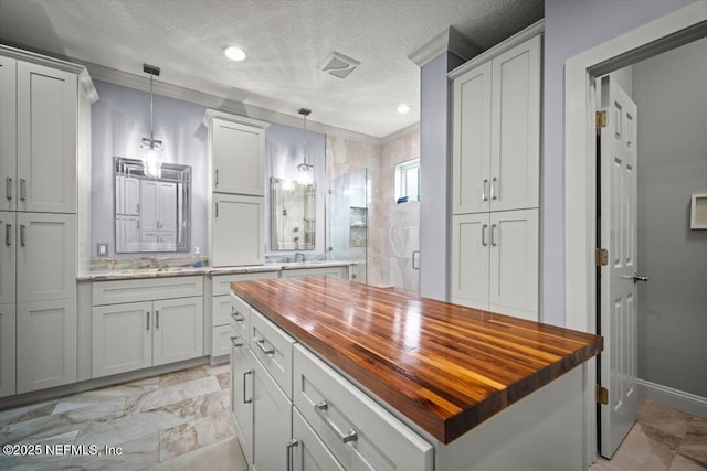 1714 Chatham Village Dr, Fleming Island, FL 32003 - kitchen featuring wood counters, a textured ceiling, hanging light fixtures, a center island, and recessed lighting