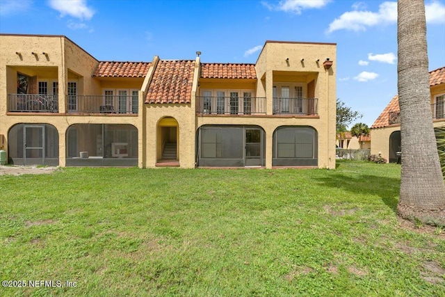 6655 Bell Tower Ct Unit 1, Jacksonville, FL 32217 - rear view of house featuring a tile roof, a balcony, stucco siding, and a lawn