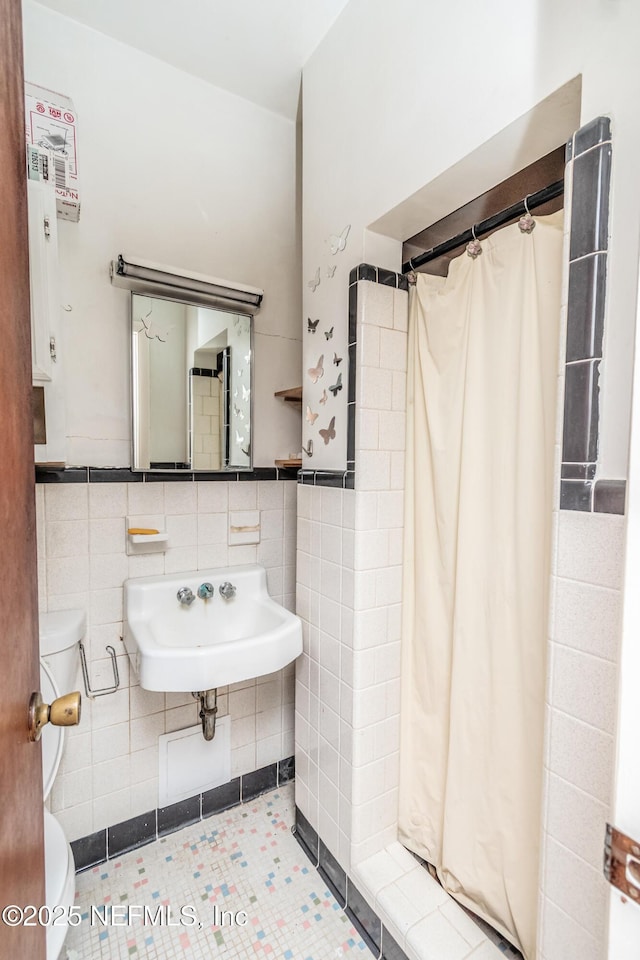 1165 5th St, Macclenny, FL 32063 - bathroom featuring toilet, a sink, tile walls, a shower with shower curtain, and tile patterned flooring