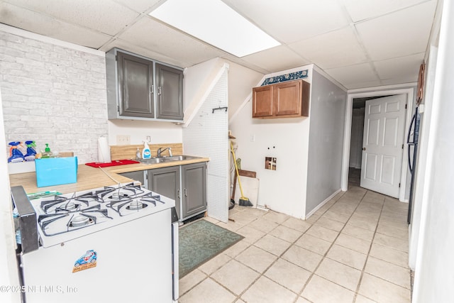 1165 5th St, Macclenny, FL 32063 - kitchen featuring a drop ceiling, white gas range oven, light countertops, light tile patterned floors, and a sink