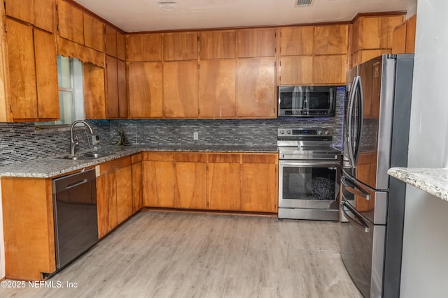 1165 5th St, Macclenny, FL 32063 - kitchen with stainless steel appliances, tasteful backsplash, light wood-style flooring, brown cabinets, and light stone counters