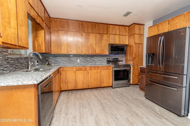 1165 5th St, Macclenny, FL 32063 - kitchen with stainless steel appliances, tasteful backsplash, light wood-style flooring, and brown cabinets