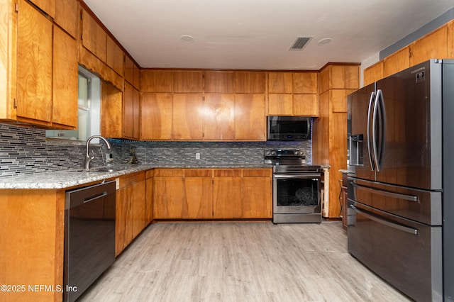 1165 5th St, Macclenny, FL 32063 - kitchen with appliances with stainless steel finishes, light wood-type flooring, decorative backsplash, and brown cabinetry