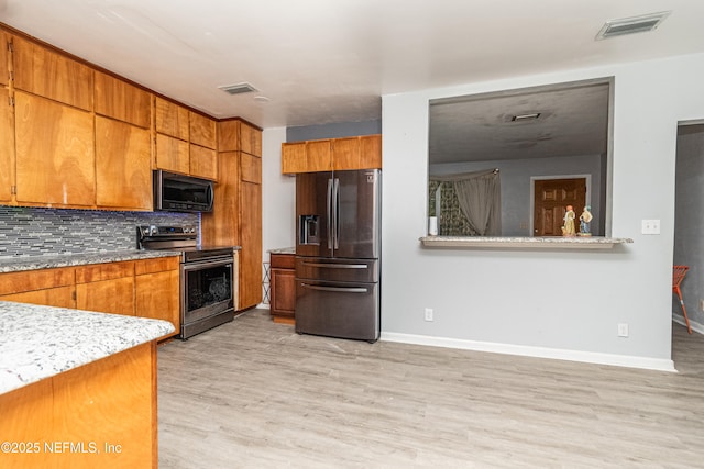 1165 5th St, Macclenny, FL 32063 - kitchen featuring stainless steel appliances, decorative backsplash, brown cabinetry, light wood-style flooring, and light countertops