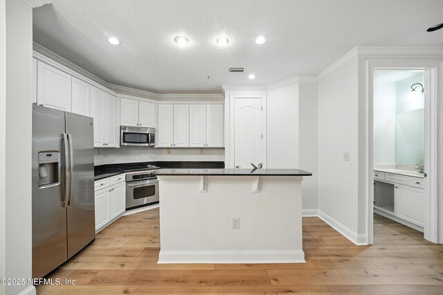 4300 S Beach Pkwy Unit 3214, Jacksonville Beach, FL 32250 - kitchen with stainless steel appliances, dark countertops, white cabinets, light wood finished floors, and ornamental molding
