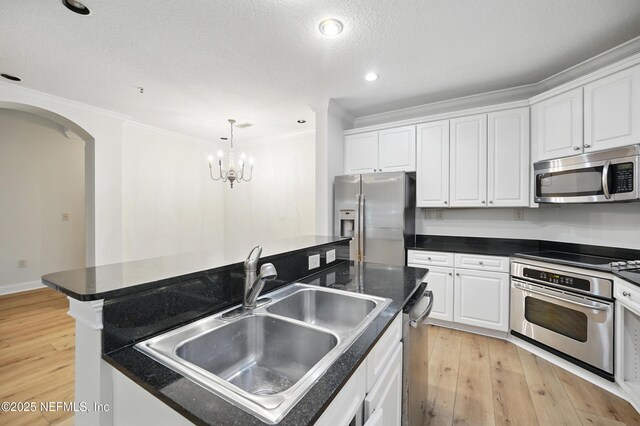 4300 S Beach Pkwy Unit 3214, Jacksonville Beach, FL 32250 - kitchen featuring appliances with stainless steel finishes, a sink, white cabinets, arched walkways, and dark countertops