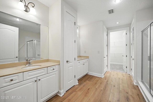 4300 S Beach Pkwy Unit 3214, Jacksonville Beach, FL 32250 - bathroom featuring a shower stall, two vanities, hardwood / wood-style floors, a spacious closet, and recessed lighting