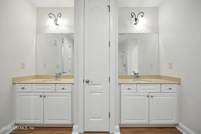 4300 S Beach Pkwy Unit 3214, Jacksonville Beach, FL 32250 - bathroom with two vanities, a shower with door, baseboards, and wood finished floors