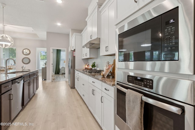 101 Bucktail Ave, Ponte Vedra, FL 32081 - kitchen featuring appliances with stainless steel finishes, under cabinet range hood, dark stone countertops, white cabinets, and tasteful backsplash