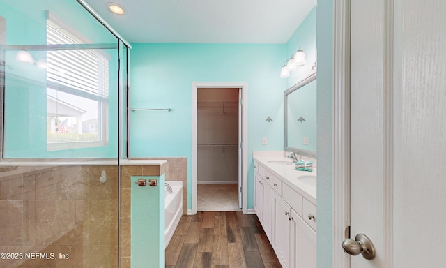 4171 Fishing Creek Ln, Middleburg, FL 32068 - bathroom with wood finished floors, tiled shower, a bath, double vanity, and a spacious closet