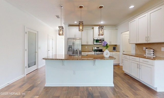 4171 Fishing Creek Ln, Middleburg, FL 32068 - kitchen with appliances with stainless steel finishes, ornamental molding, decorative backsplash, a center island with sink, and a breakfast bar area