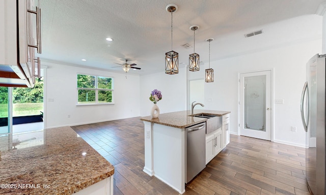 4171 Fishing Creek Ln, Middleburg, FL 32068 - kitchen featuring appliances with stainless steel finishes, ceiling fan, wood finished floors, open floor plan, and stone counters