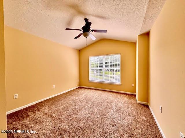 8561 Little Swift Cir Unit 32D, Jacksonville, FL 32256 - empty room with ceiling fan, carpet floors, a textured ceiling, vaulted ceiling, and baseboards