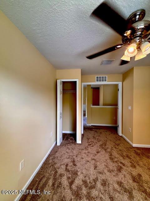 8561 Little Swift Cir Unit 32D, Jacksonville, FL 32256 - unfurnished bedroom featuring carpet floors, baseboards, a textured ceiling, a ceiling fan, and a closet