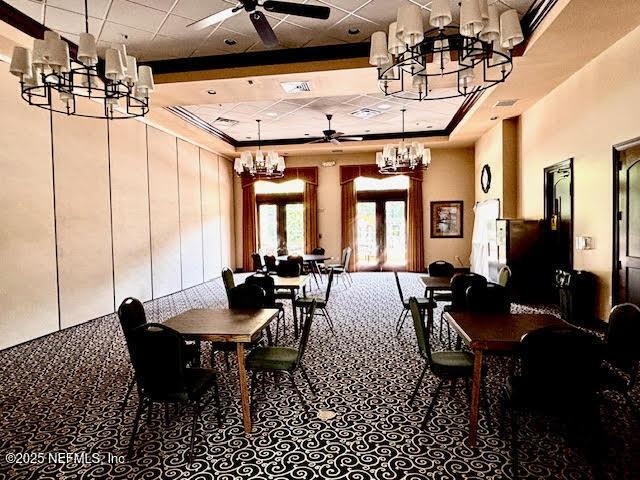 8561 Little Swift Cir Unit 32D, Jacksonville, FL 32256 - carpeted dining area with a chandelier, a ceiling fan, a tray ceiling, a drop ceiling, and a towering ceiling