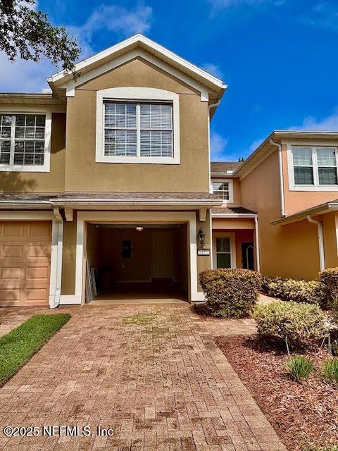 8561 Little Swift Cir Unit 32D, Jacksonville, FL 32256 - view of front facade with stucco siding, an attached garage, and decorative driveway