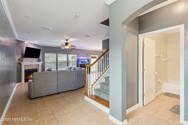 96290 Coral Reef Rd, Yulee, FL 32097 - living room with light tile patterned floors, ceiling fan, a fireplace, ornamental molding, and stairs