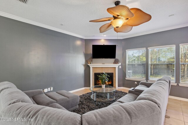 96290 Coral Reef Rd, Yulee, FL 32097 - living room featuring light tile patterned floors, a tiled fireplace, a ceiling fan, baseboards, and crown molding