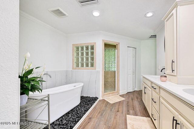 4966 Harvey Grant Rd, Fleming Island, FL 32003 - bathroom with a freestanding bath, wood finished floors, double vanity, a stall shower, and crown molding
