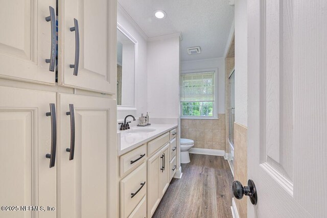 4966 Harvey Grant Rd, Fleming Island, FL 32003 - full bath with toilet, vanity, tile walls, wood finished floors, and crown molding