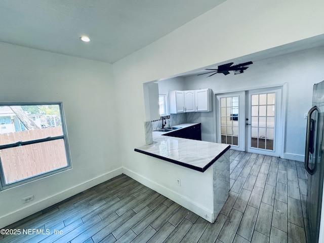 1041 E 14th St, Jacksonville, FL 32206 - kitchen featuring wood finished floors, white cabinets, stainless steel fridge with ice dispenser, baseboards, and a peninsula